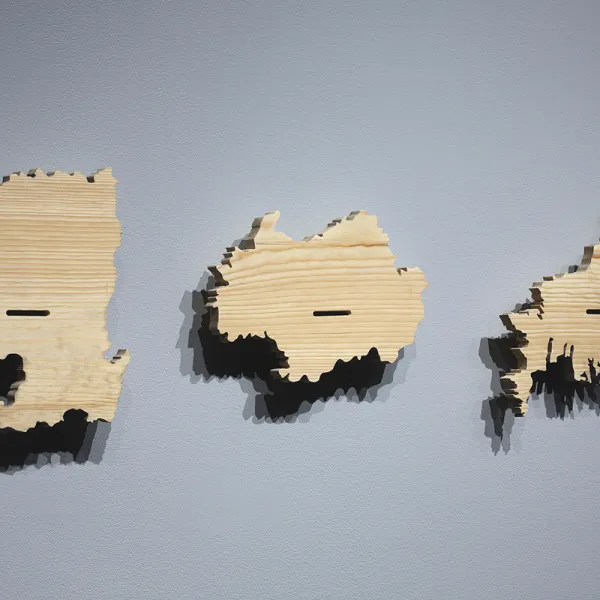 Three wooden blocks in the shape of three different Korean provinces or cities, mounted on a wall.