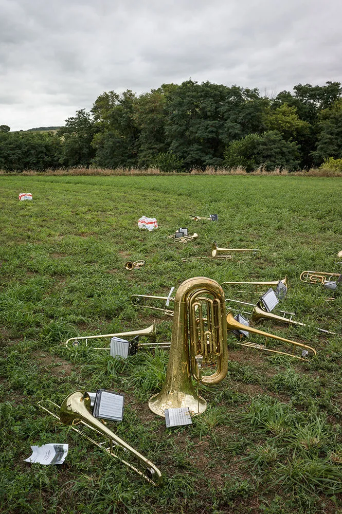 Groundbreaking, Prescott High School, 2014; Brass band instruments strewn across a grassy field with trees in the background