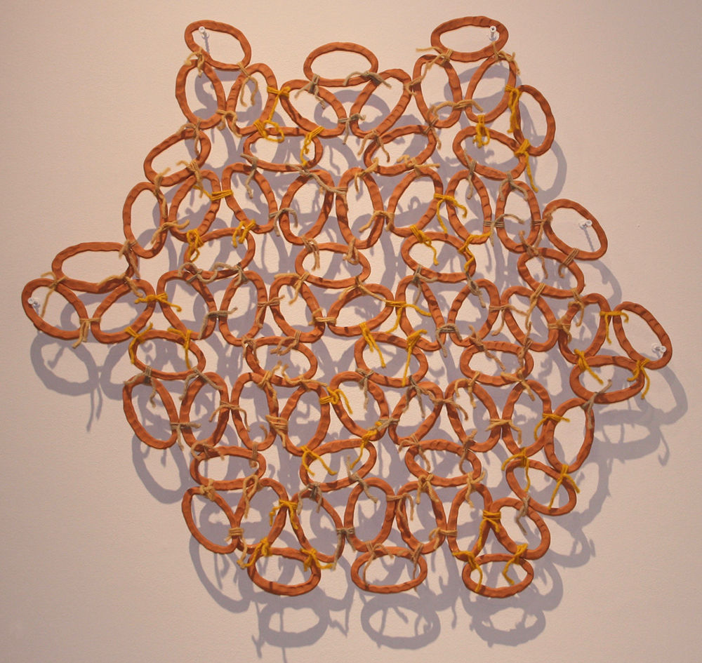 Dozens of thin ceramic oval outlines bound together into a cluster by twine