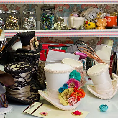 The top of a white desk full of crafting materials with fabric and buttons and sewing supplies