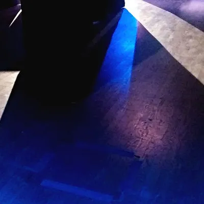 Wood floor in a dark room, with streams of white and blue light