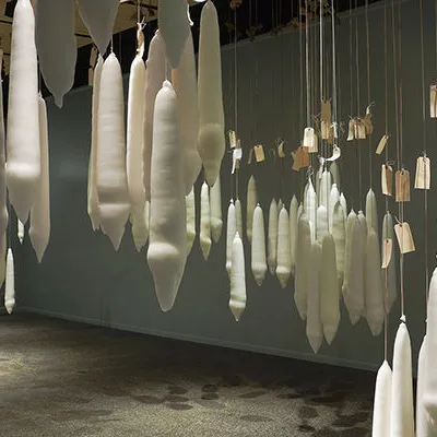 A large collection of candles dipped the same number of times as the lifespans of people attached to them; they hang from the cieling in various arrangements.