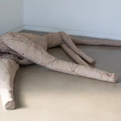 a oversize sculture of a body made of Mixed media including wool felt, fiber fill, sewing patterns, cotton thread, sewing hardware.