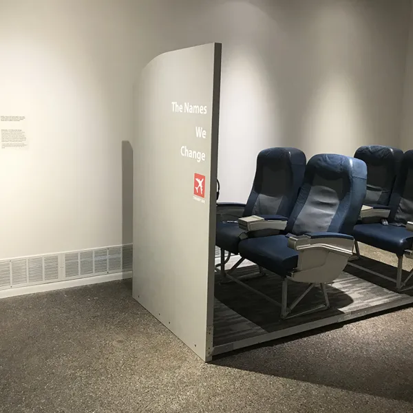 Katayoun Amjadi, The Names We Change: Transit-Air, 2020, repurposed airplane seats, iPads, HD video interviews, Namezines Four airplane seats in two rows of two.
