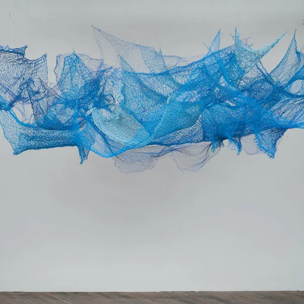 Carolyn Halliday, "COVID 19 Blue," hanging sculpture: knit wire, 40” x 94” x 52” A blue net, tacked to the ceiling in several different places.
