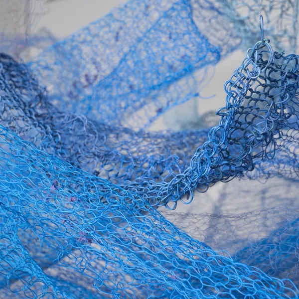 A close-up of blue knit wire strung form the ceiling in several different places.