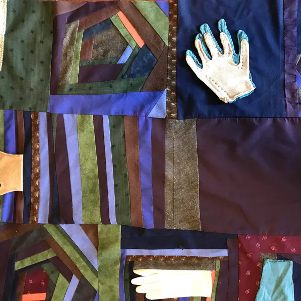 Rita Collins, "Covid Quilt #1 (Segment B)," fabric, gloves, thread, entire quilt: 39” x 44” This quilt segment contains four gloves of different types and colors, pointing in different directions. It also contains panels of bands of different colors, sometimes layered in the shape of a pentagon.