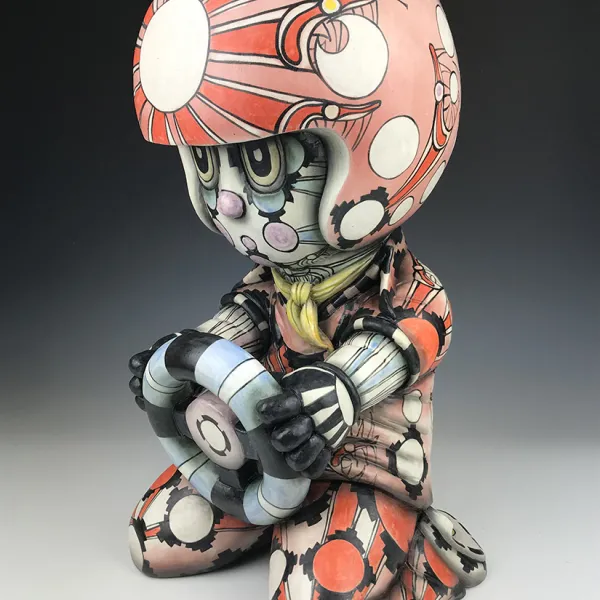 Guillermo Guardia, Meteorito GGY, 2019, stoneware, underglazes, clear glaze, 24 x 12” A ceramic human-like figure with a helmet on its head and a steering wheel in its hands.
