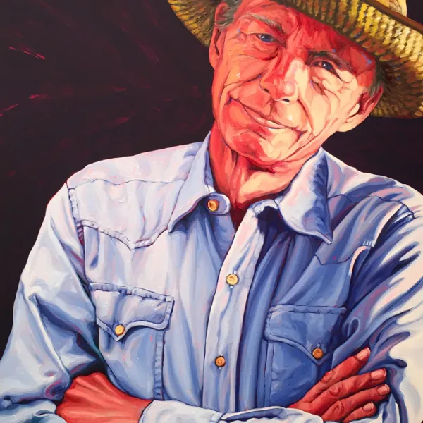 Jim Urbach Remembered, 2017. Oil on panel, 24 x 18". Man with his arms crossed, wearing a casual blue shirt and a (Western?, Southwestern?) wide-brimmed hat with a (possibly Native American Indian) design on it.