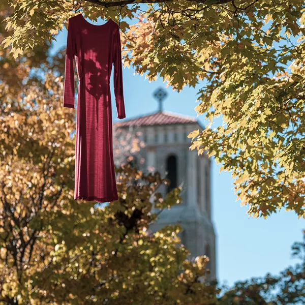 Red dress hung on tree on campus with chapel in background