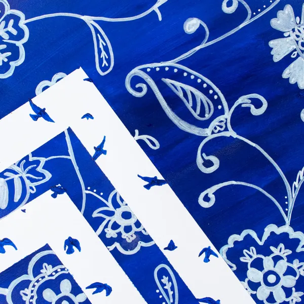 painting of white bandanna pattern flowers on blue background, with white chevrons and birds in silhouette