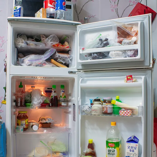 A small refrigerator with the refrigerator and freezer doors open, displaying their contents.