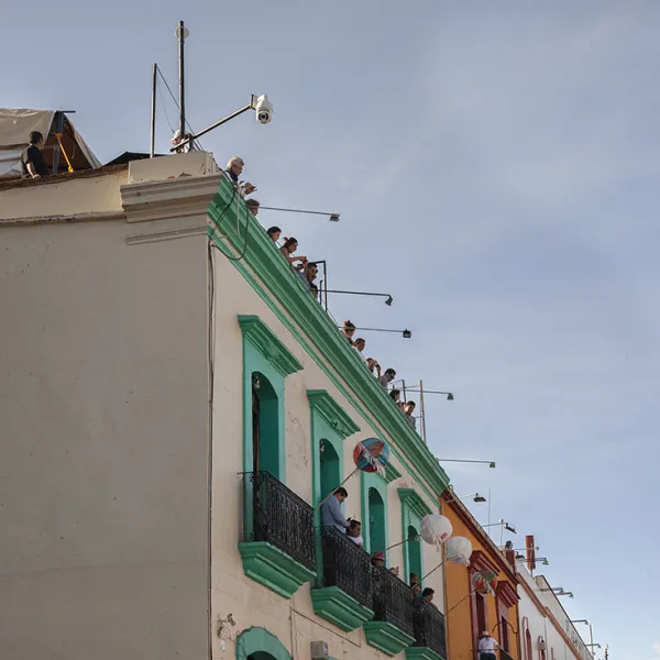 Colorful buildings with people standing on balconies and also on the roof. Andador Turistico is a tourst attraciton in Oaxaca, Mexico.
