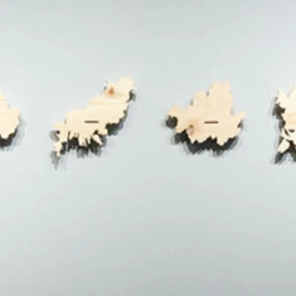 Twelve wooden shapes of different Korean provinces or cities mounted on a wall in a straight line, with speakers at either end.