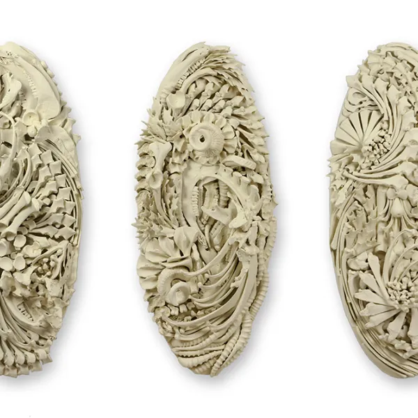 Three vertical oval sculptures with intricate patterns.