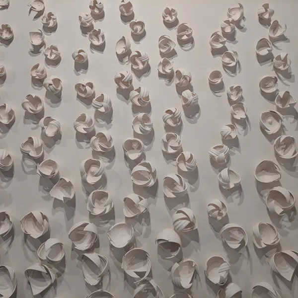 Many small sculptures made of pieces of bowls, laid out in a vine-like pattern.