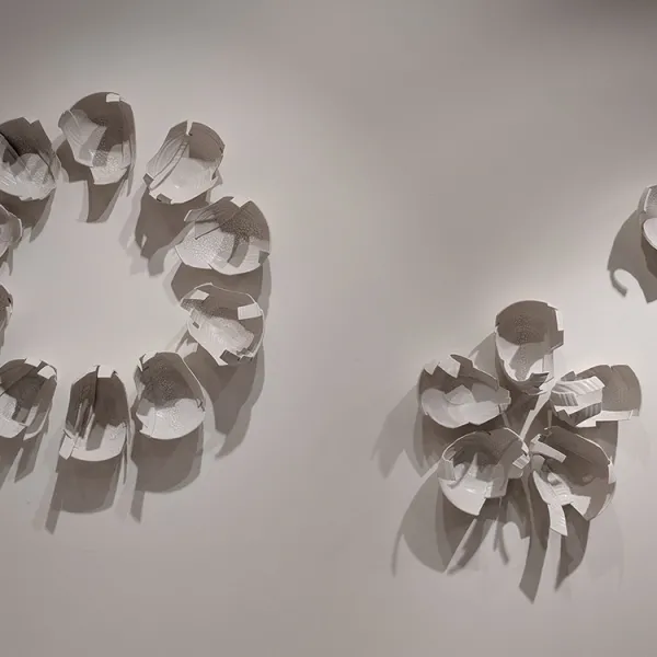 Three wall sculptures made of pieces of bowls, like lily pads - one large circle, one small circle, and one five-petaled flower.