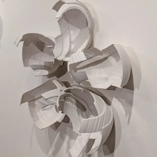 Abstract wall sculpture made of pieces of bowls, in the shape of a five-petaled flower.