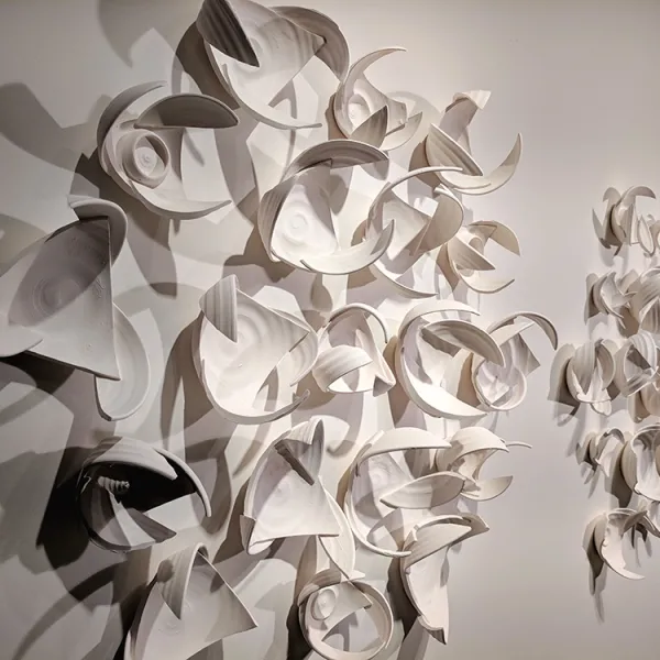 Abstract wall sculpture made of pieces of bowls, constructed so they give the impression of wings.