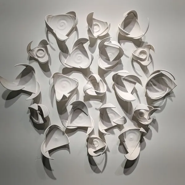 Abstract wall sculpture made of pieces of bowls, constructed so they give the impression of wings.