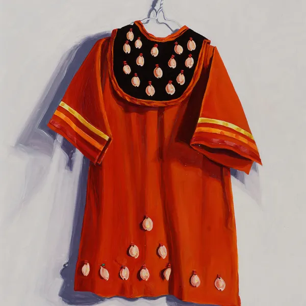 Native American dance outfit on a hanger. Orange dress with ribbons banding the ends of the sleeves, and cowrie shells on a black bib/bodice, and more cowrie shells at the hem of the dress.