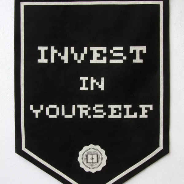 Black flag with the text "Invest in yourself" written on it and a logo below