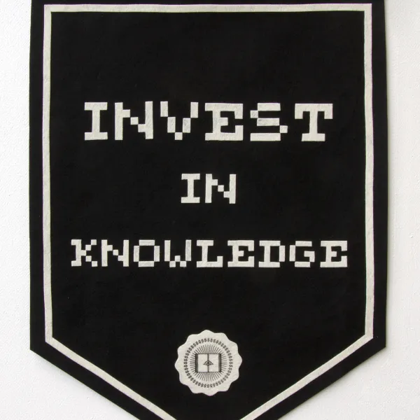 Mens Corpusque, 2023, polyester felt, serigraph, 34" x 24" Black flag with the text "Invest in knowledge" written on it and a logo below
