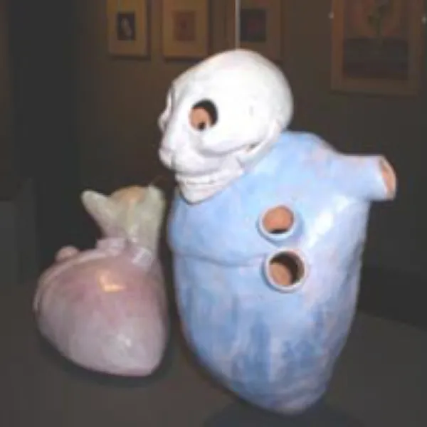 Paired ceramic sculptures of blue and red hearts, one with a cat head looking up at the larger with a cat skull.