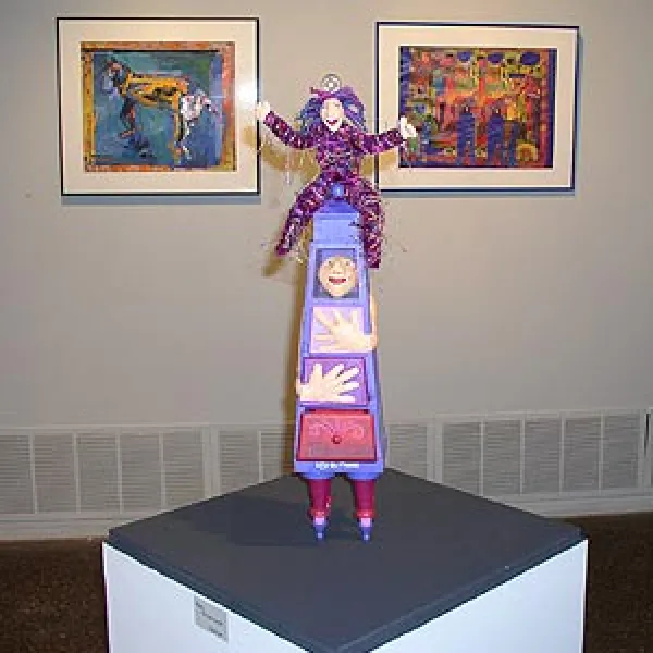 Sculpture of colorful clowns standing on one another to form a tower.