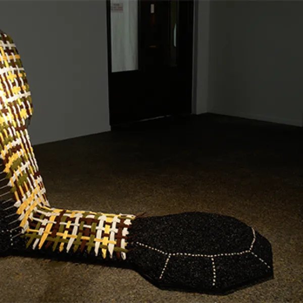 A large abstract sculpture made of asphalt, beans, fabric, and steel.