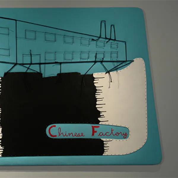 Artwork made from fabric, paint, and string meant to depict a factory.