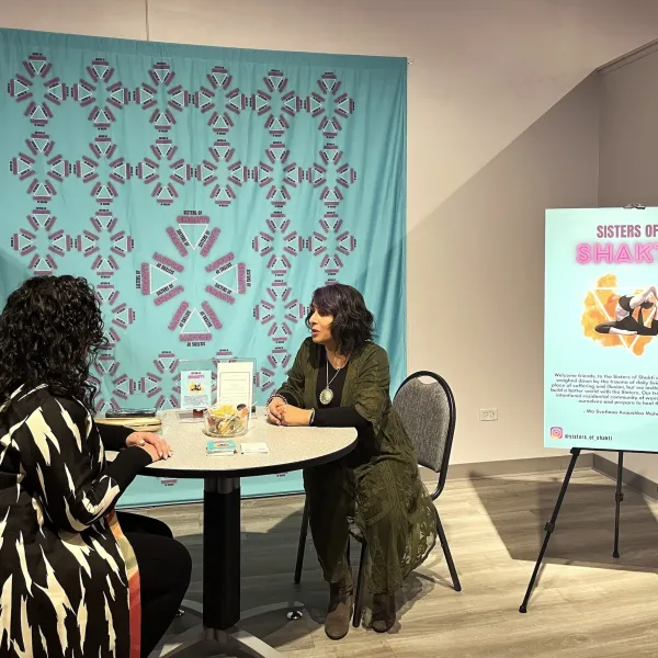 Sisters of Shakti; Interactive installation, table with postcards, a bowl of lollipops and a stamp, two chairs, fabric banner, poster on signboard