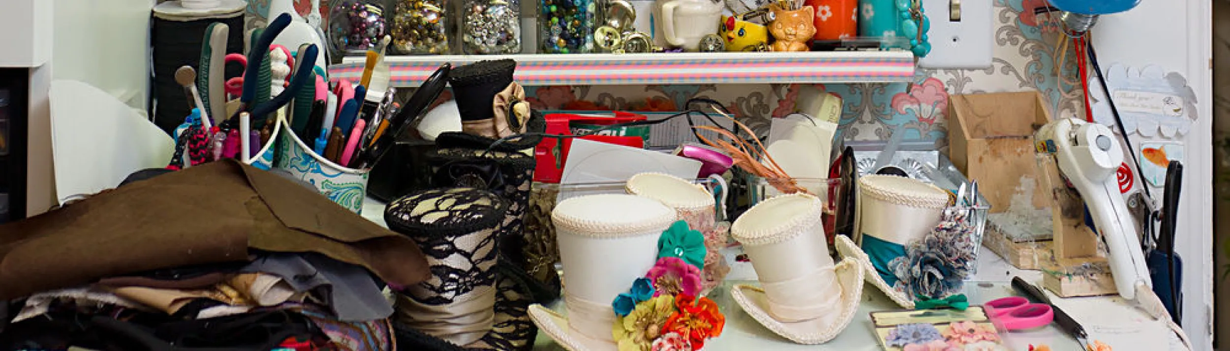 The top of a white desk full of crafting materials with fabric and buttons and sewing supplies