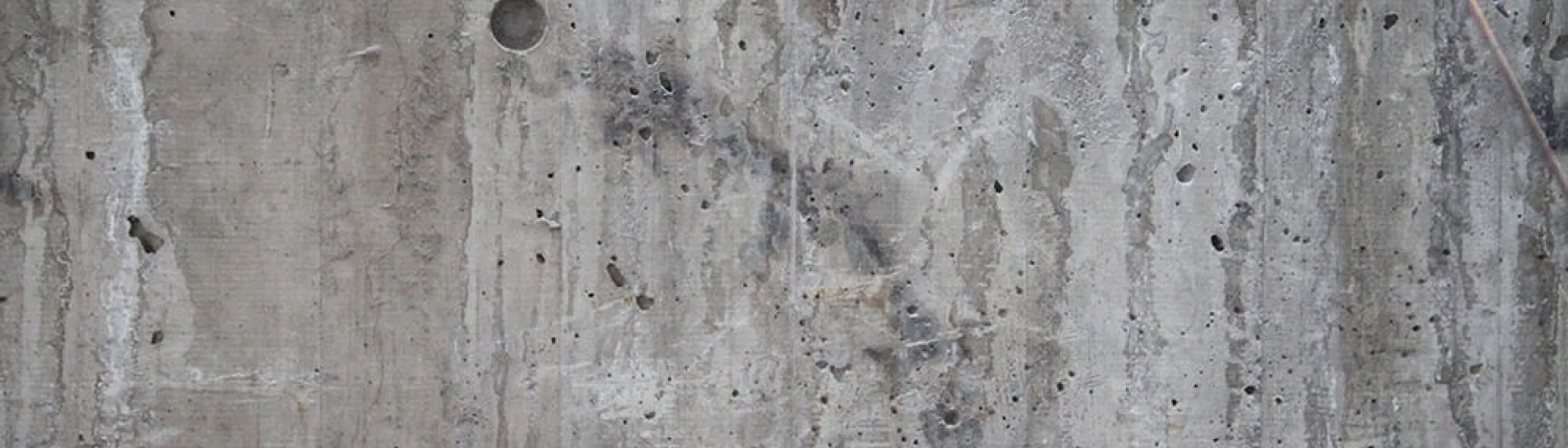 Photo of a concrete wall covered in water stains and pock marks