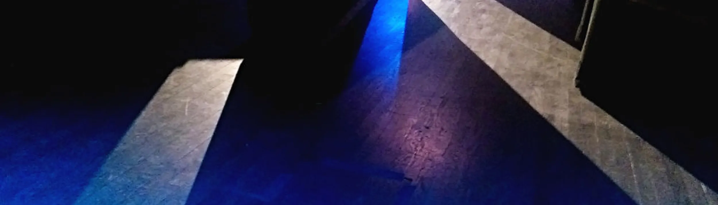 Wood floor in a dark room, with streams of white and blue light