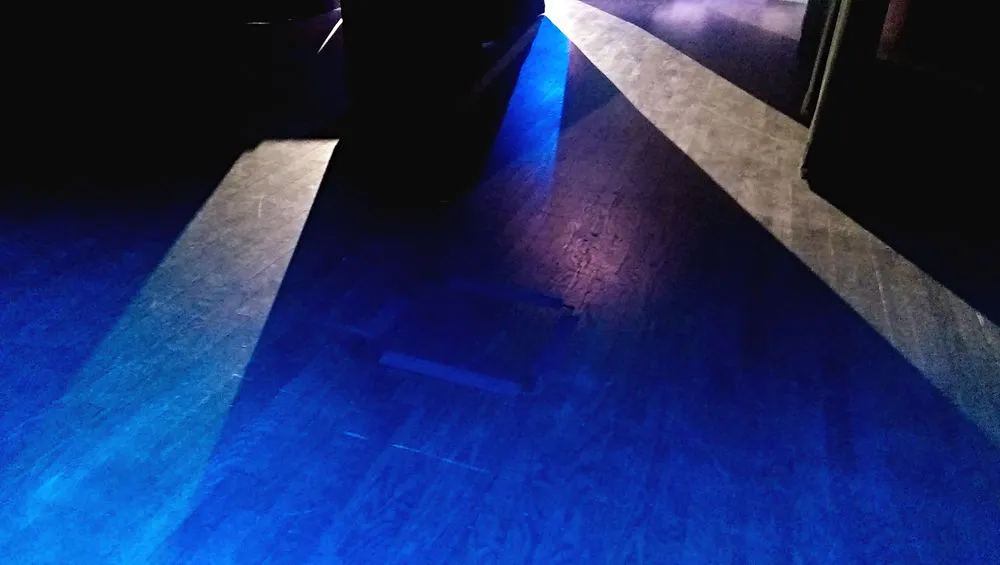 Wood floor in a dark room, with streams of white and blue light