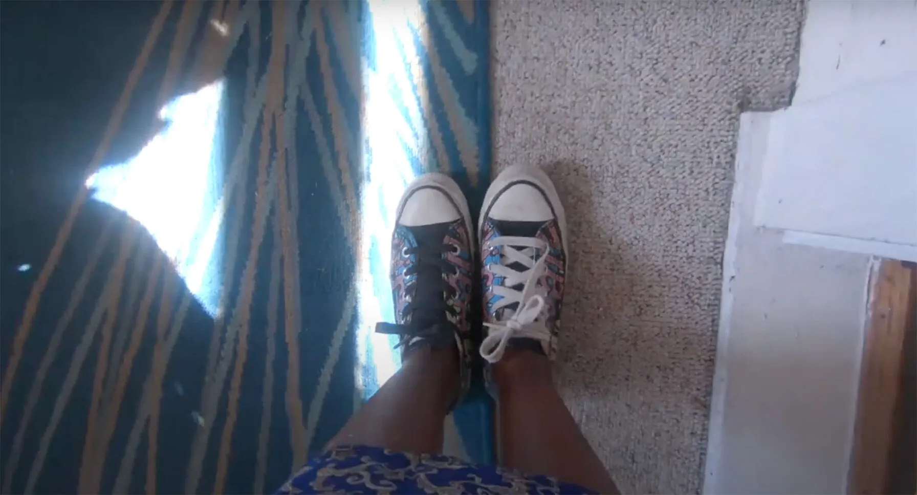 "Video Still, This is After" - Screenshot from a video of camera looking down at a pair of sneakers on a person's feet