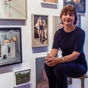 Artist Kristie Bretzke seated by wall of paintings